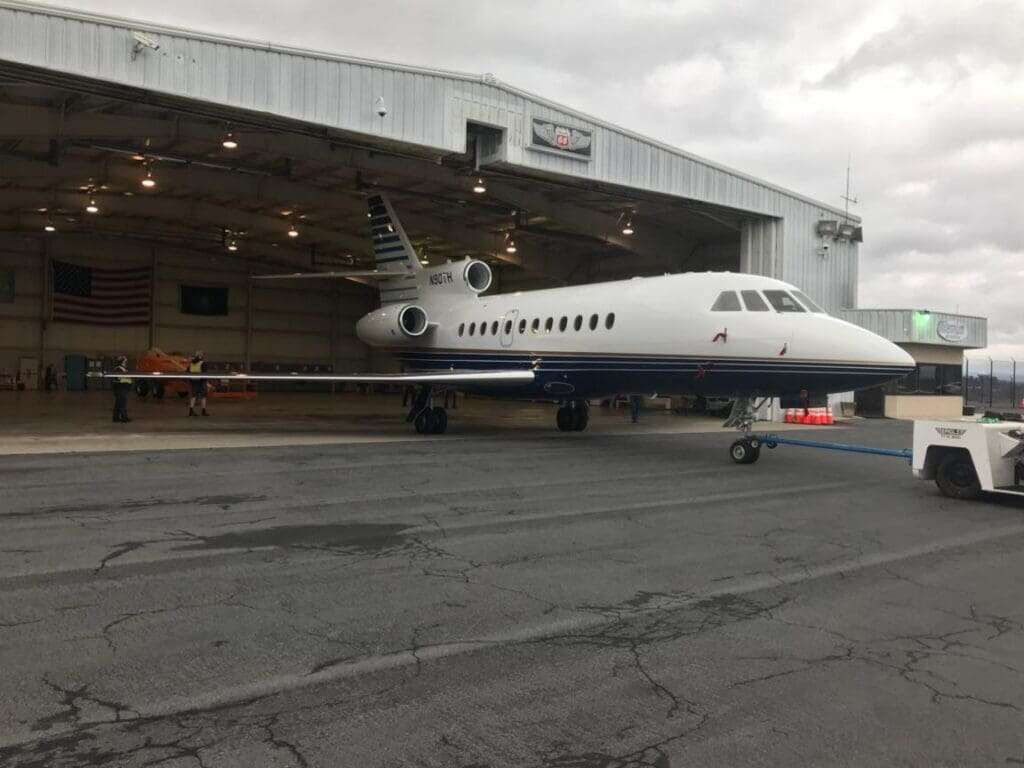 Corporate jet being towed out of modified aircraft hangar with Phillips 66 signage