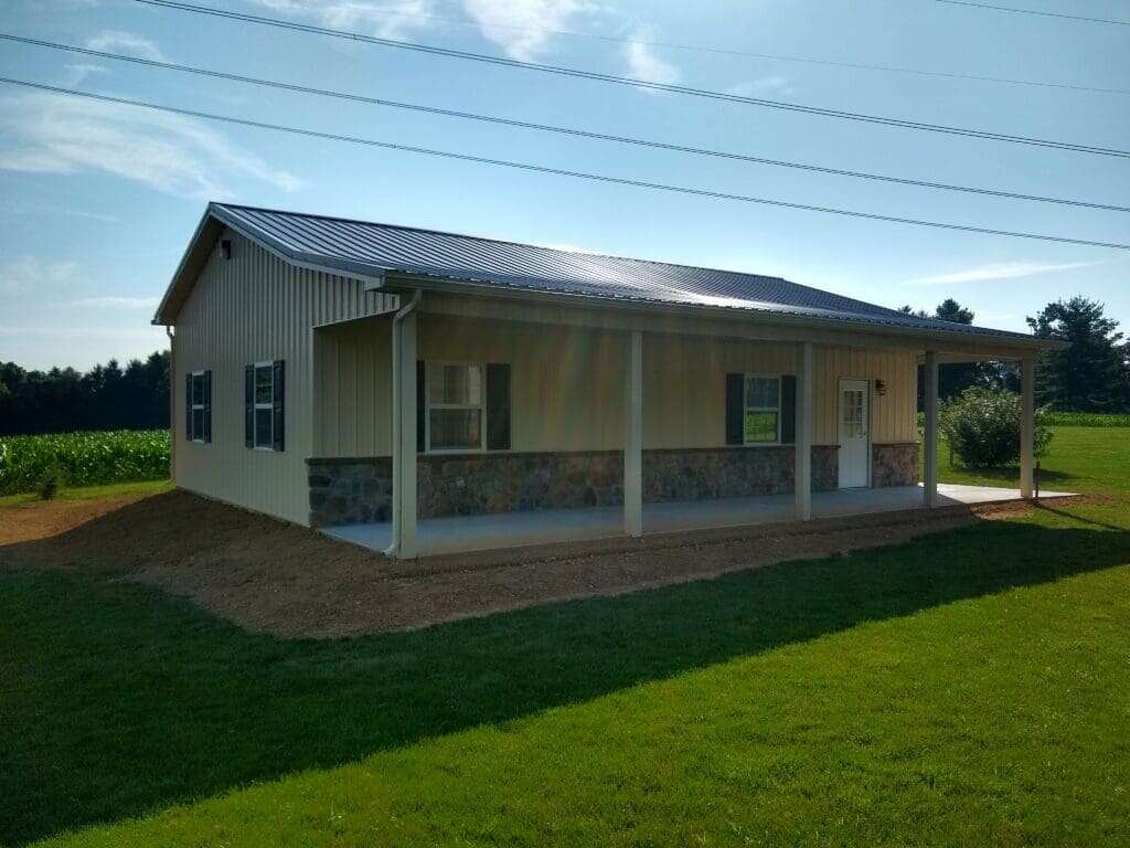 Post-frame garage with tan metal siding, metal roof, covered front porch with columns and stone wainscot
