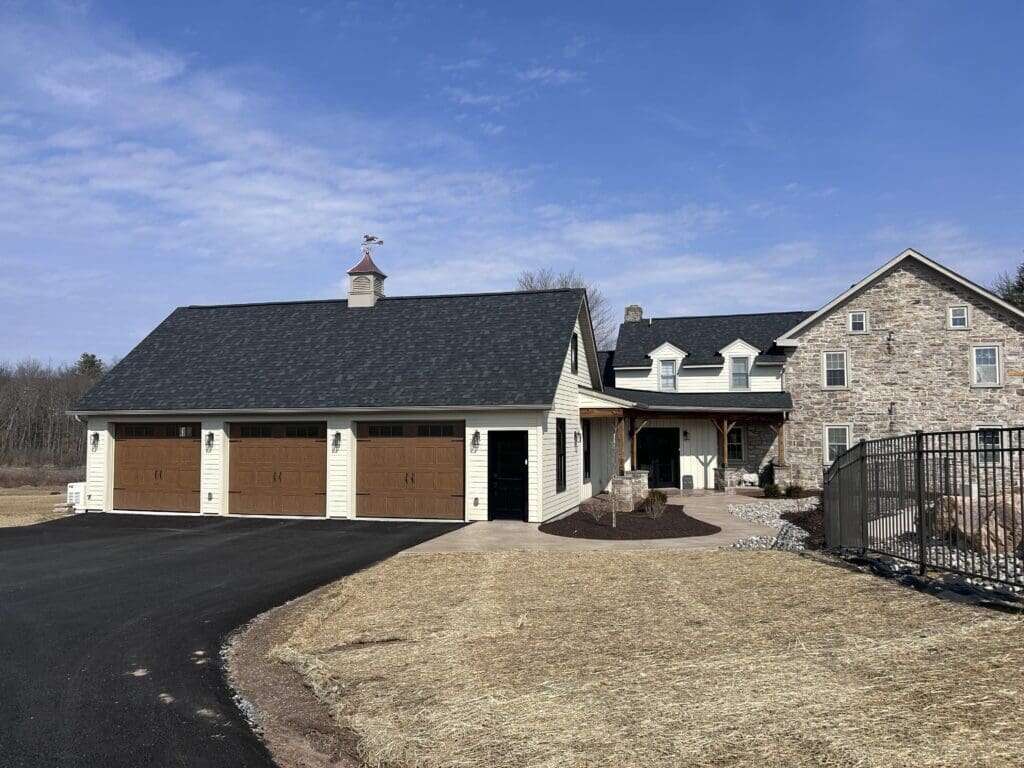 Detached garage addition with cupola and carriage doors connected by breezeway to original stone farmhouse