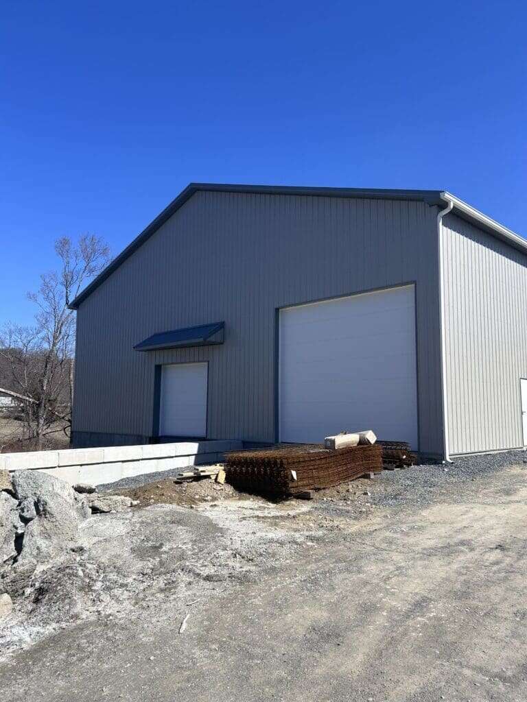Front of grey post-frame commercial storage building with large overhead doors