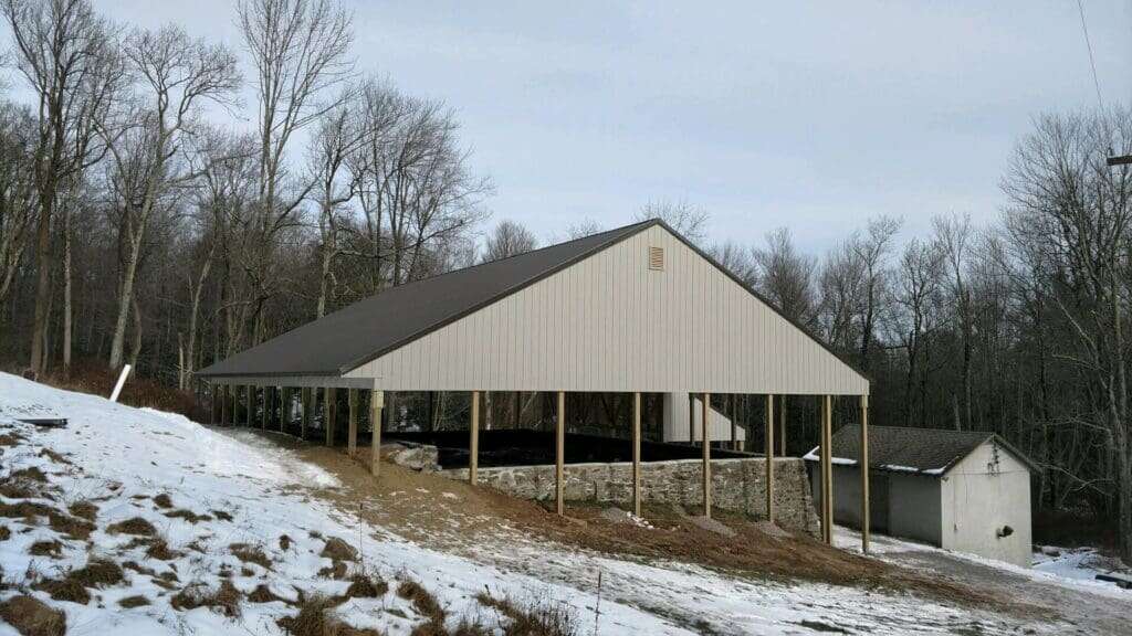 Near-complete sewage treatment building with cream metal siding and elevated stone wall foundation