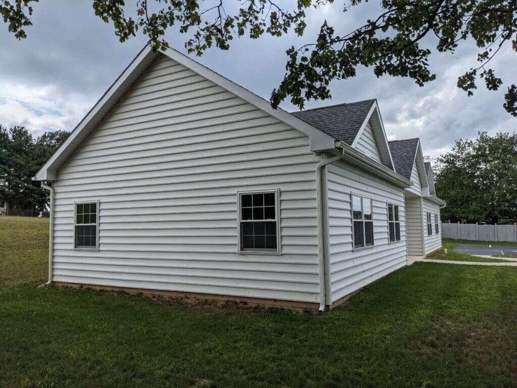 Veterinarian office building with white vinyl siding, grey shingle roof, and multiple windows