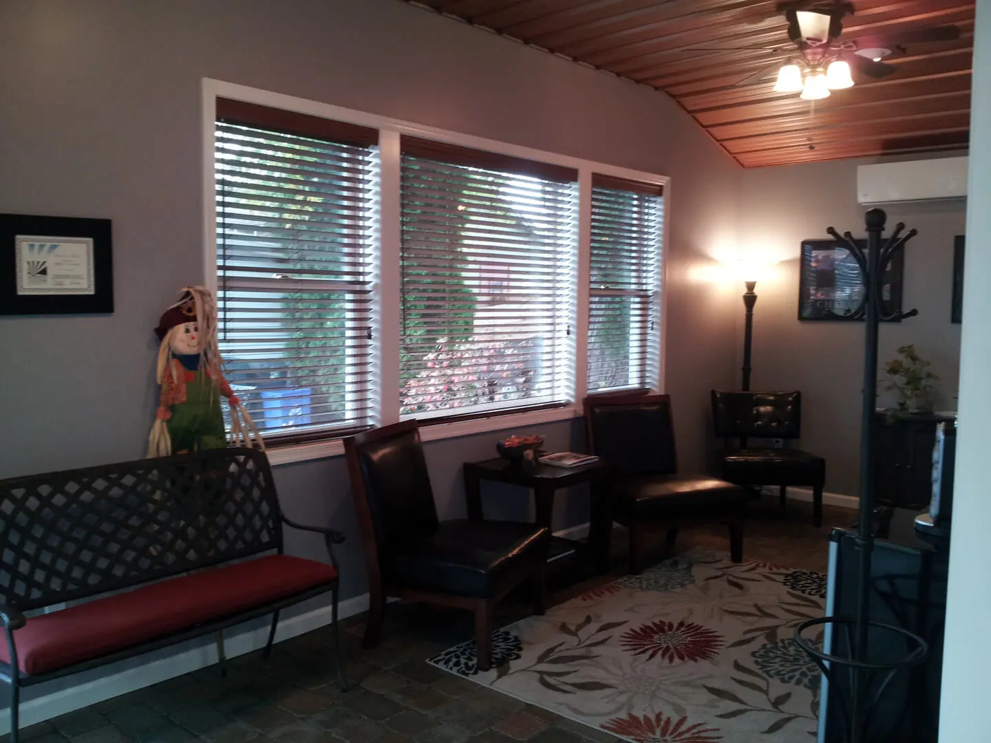 A living room with three windows and two chairs.