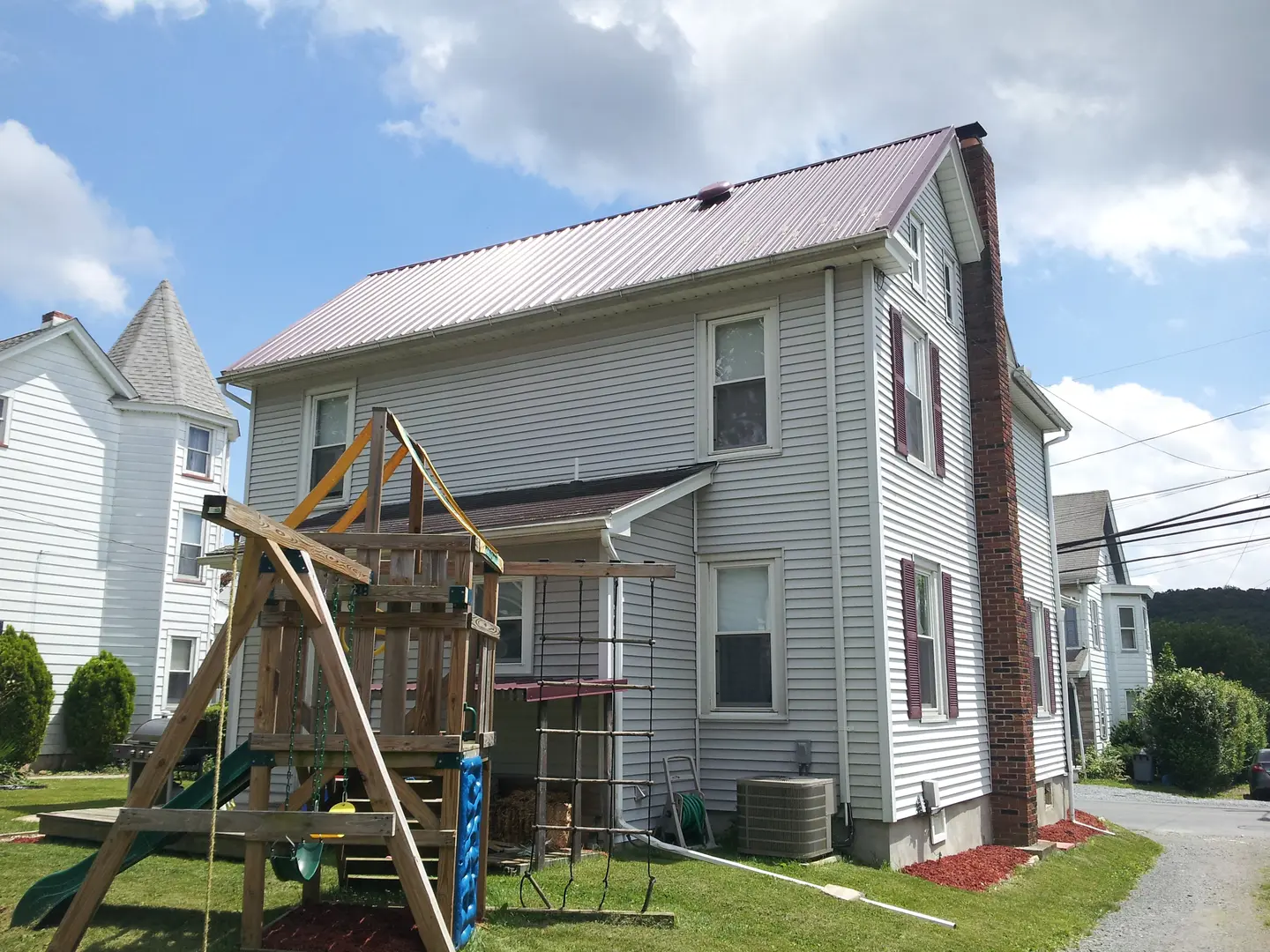 A house with a swing set in the yard.