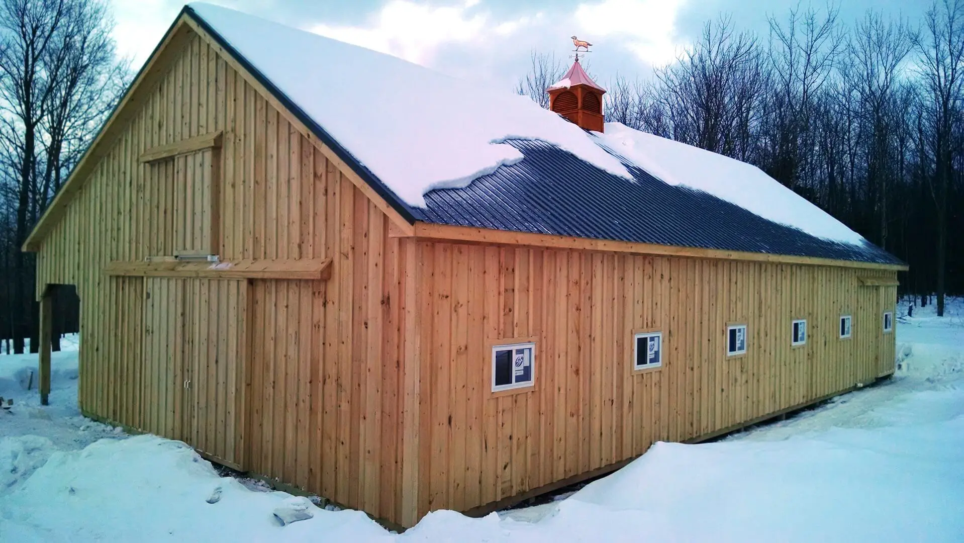 A barn with snow on the roof and windows.