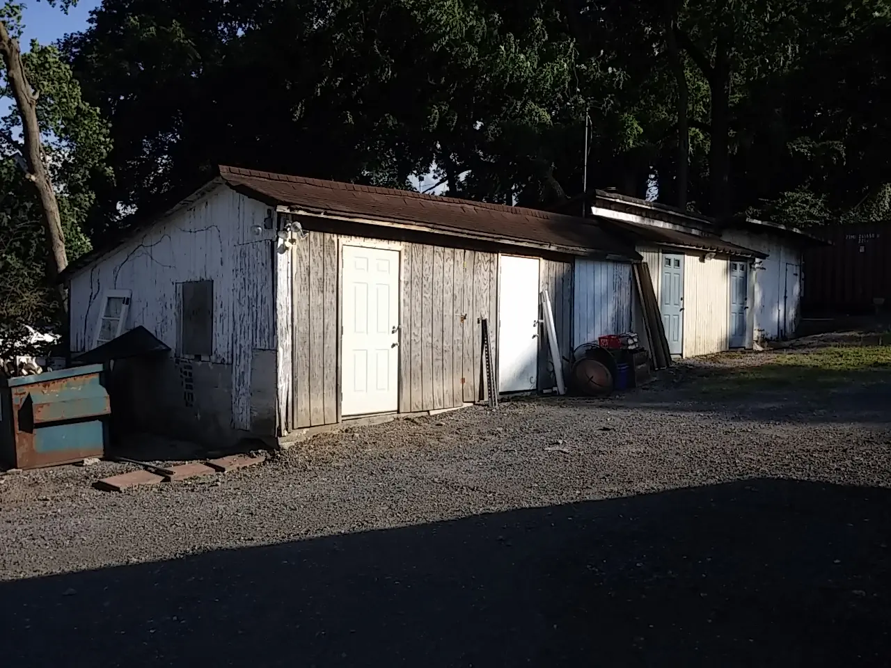 A row of white buildings sitting on top of a gravel road.