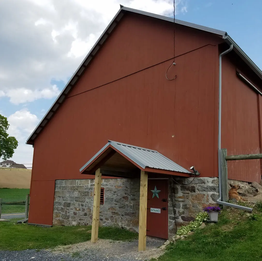 A red barn with a stone wall and door.