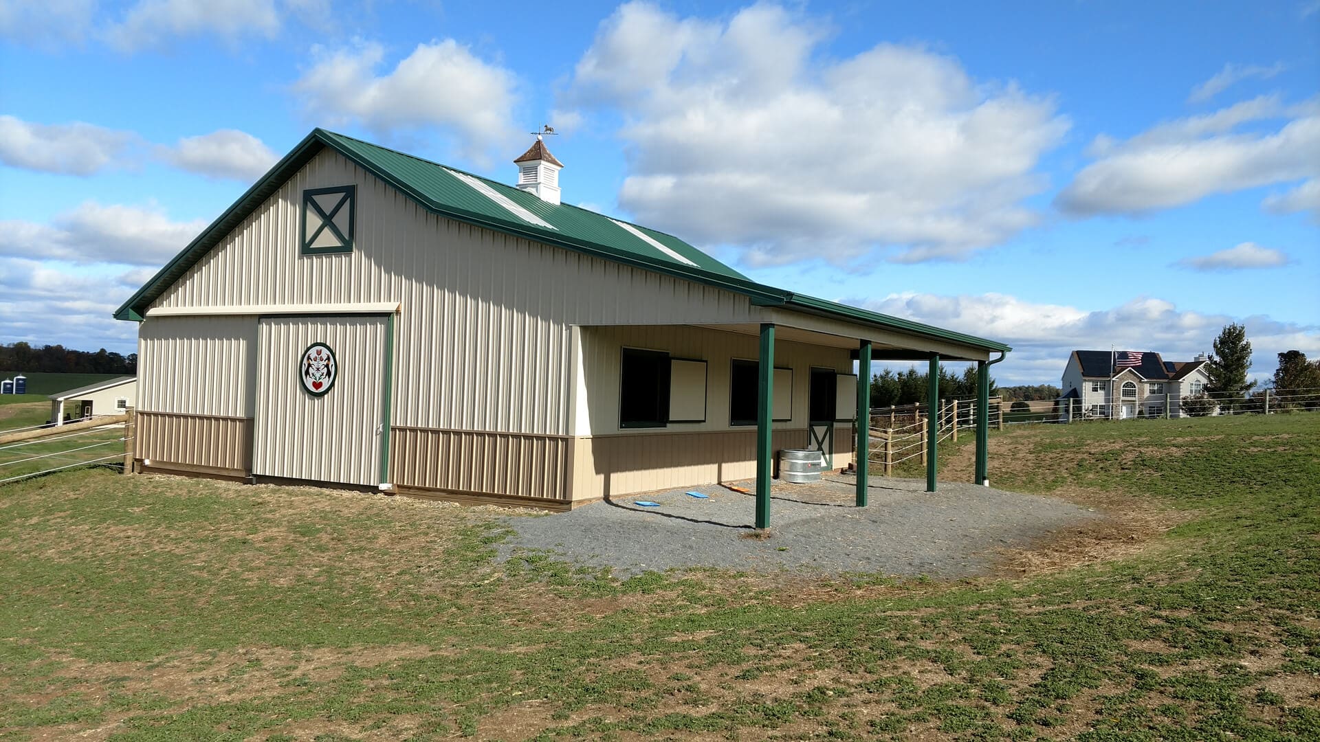 A barn with a green roof and white walls.