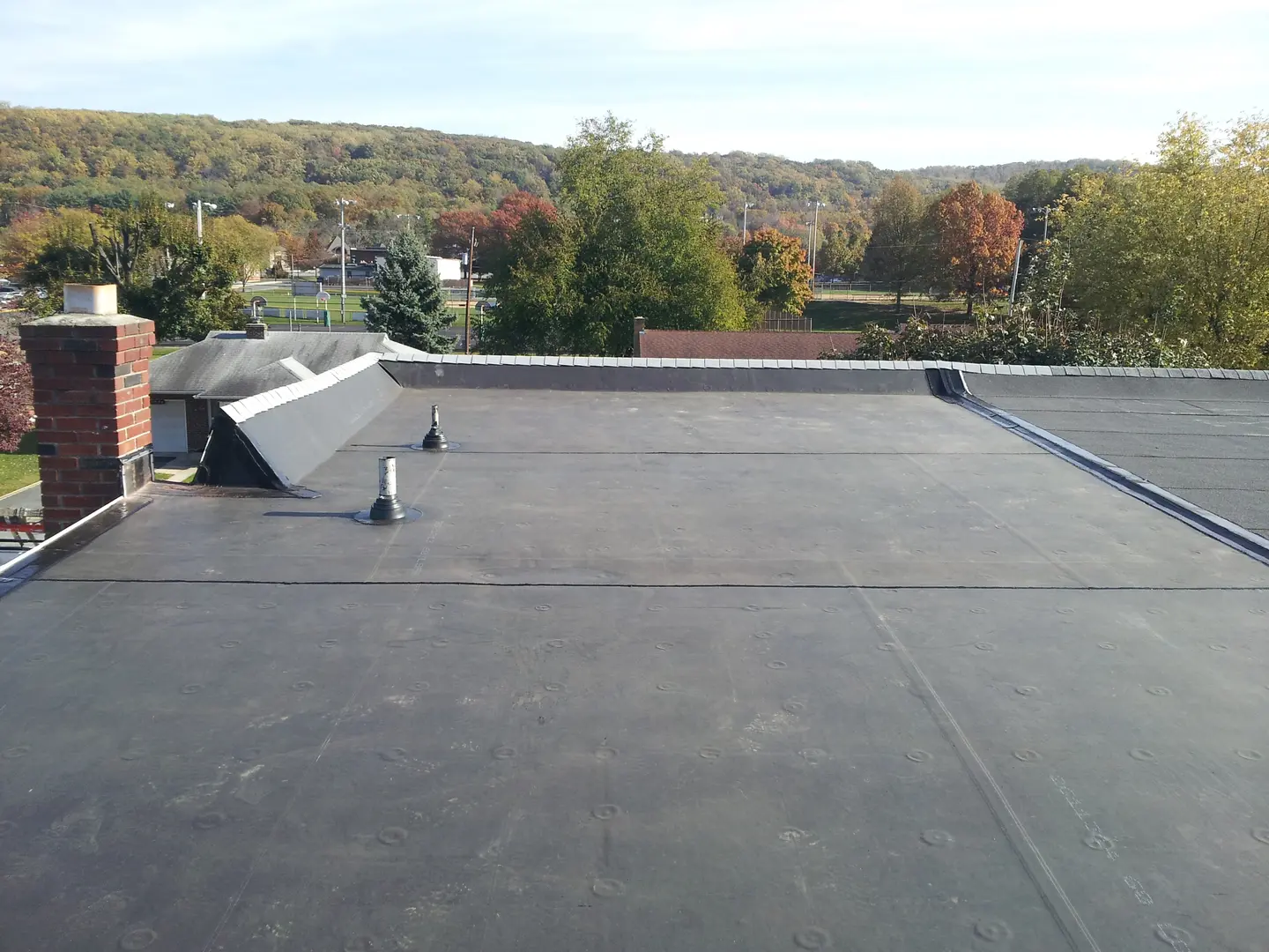 A flat roof with multiple sections and two different types of pipes.