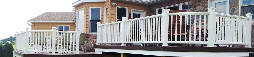 A dog is standing on the porch of a house.