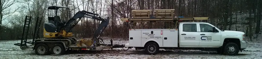 A white utility trailer with a crane on top of it.