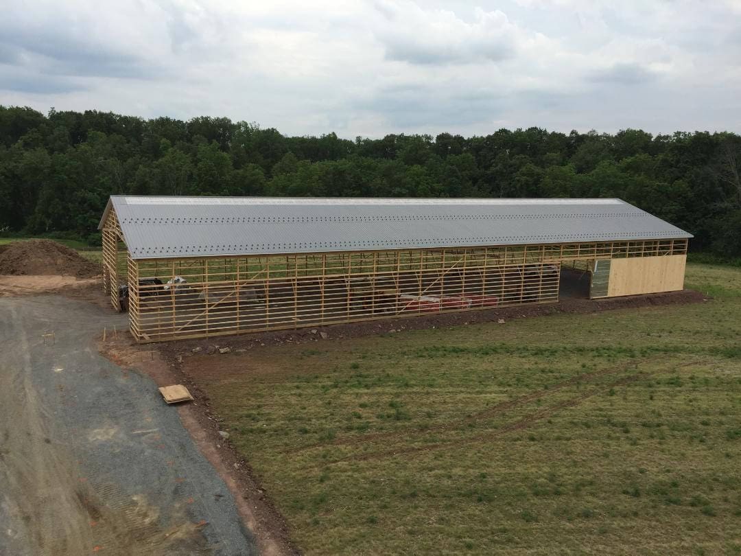 A large building with a metal roof in the middle of a field.