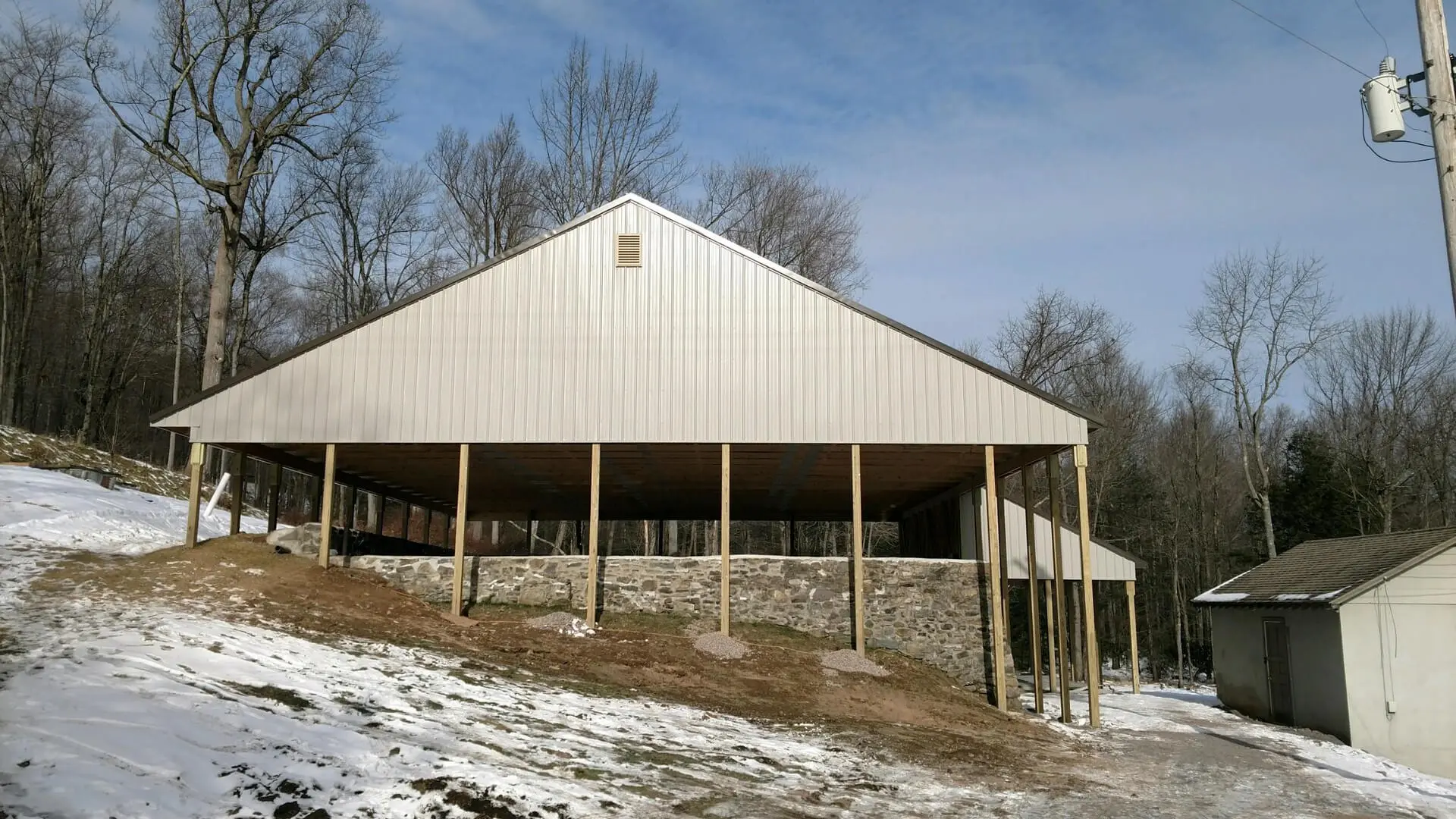 A large white barn with snow on the ground.