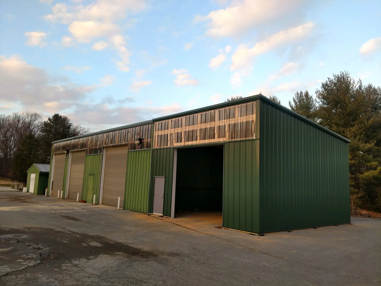 A green building with two doors and a sky background