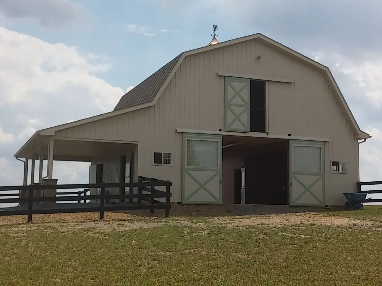 A barn with two doors and a fence in the middle of it.