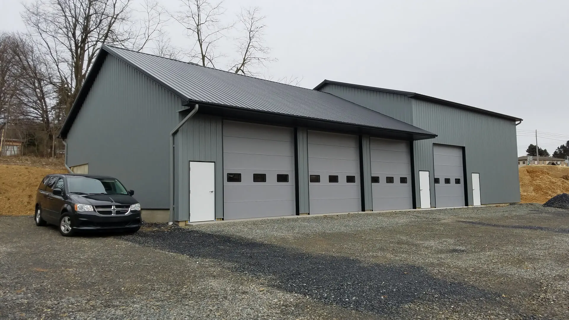 A garage with two doors and a motorcycle parked in front of it.