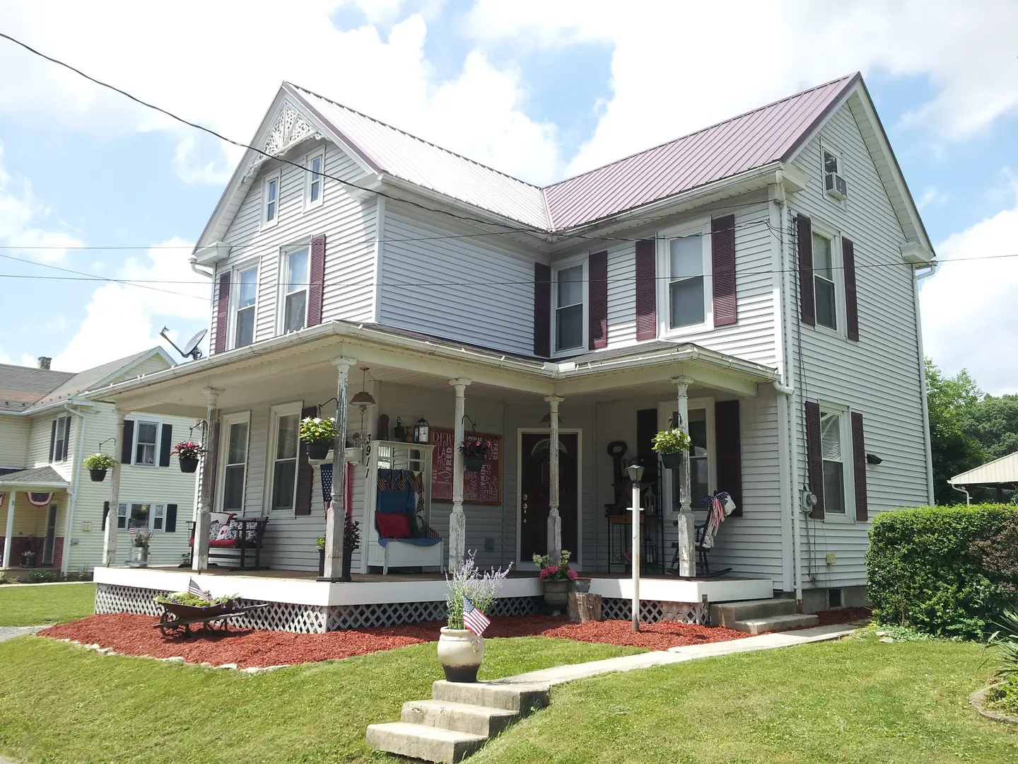 A large white house with red shutters and a porch.