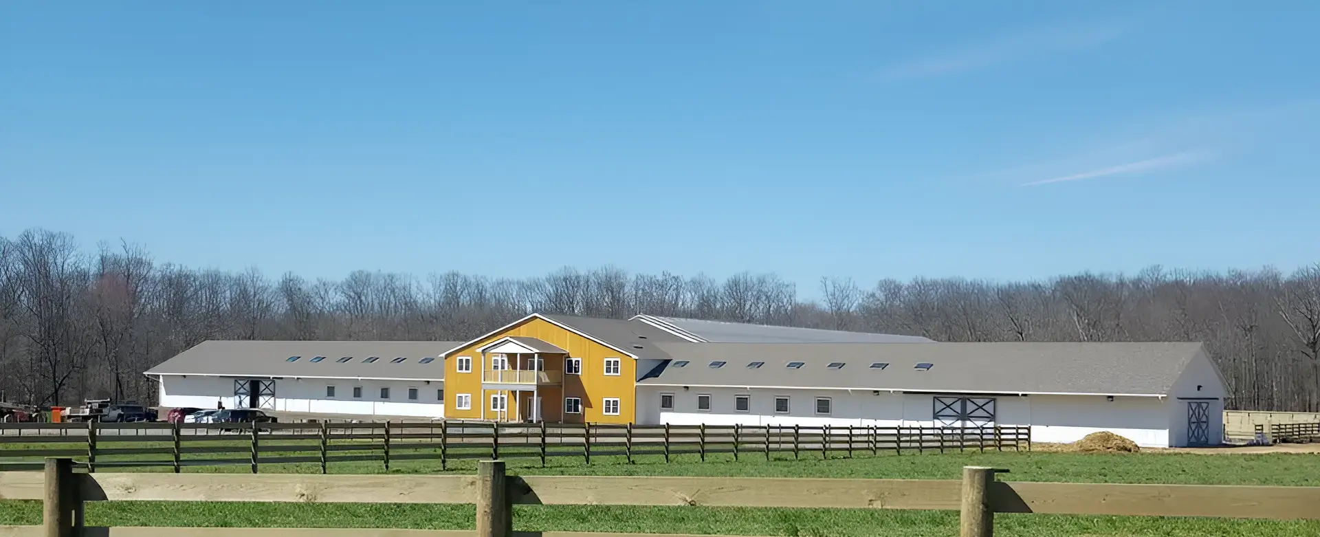 A yellow barn with a fence in front of it.