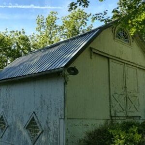 A green shed with a metal roof and a window.