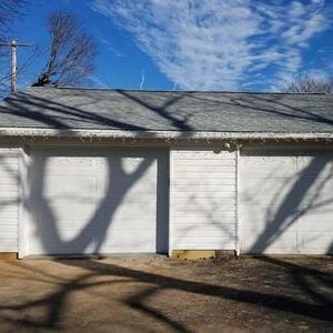 A white garage with trees in the background.